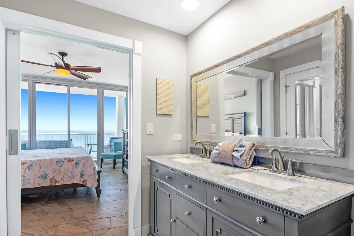 Gulf Shores condo bedroom and vanity with an ocean view through the glass doors
